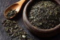 Close-up of Dried Green Tea Leaves in a Wooden Bowl with a Spoon Royalty Free Stock Photo