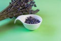 Dried lavender flowers in a white ceramic spoon and a bunch of dry lavender on a green background. Cooking, spices Royalty Free Stock Photo
