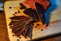 Dried meat, basturma lies on a wooden Board with capers and spices