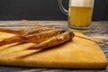 Dried mullet on a wooden Board with a mug of beer on the table. Fish and seafood cuisine. Tasty snack.