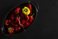 Dried multi-colored, textured chili peppers lie in black form for baking on a black stone background Royalty Free Stock Photo