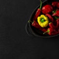 Dried multi-colored, textured chili peppers lie in black form for baking on a black stone background Royalty Free Stock Photo