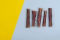 Dried natural healthy treats for dogs. Beef esophagus sticks on a yellow and blue background