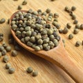 Dried okra seeds in wooden spoon, on bamboo cutting board