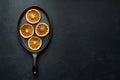 Dried orange slices on oval cast iron pan, black textured background with copy space Royalty Free Stock Photo