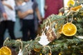 Dried orange slices and tree-shaped gingerbreads hanging on a Christmas tree, with Christmas lights and people in the background. Royalty Free Stock Photo