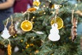 Dried orange slices and a white snowman hanging on a Christmas tree, with Christmas lights and people in the background. Royalty Free Stock Photo