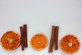 Dried oranges and cinnamon sticks on white background. Flat lay Christmas border. Royalty Free Stock Photo