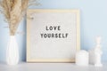 Dried pampas grass in vases, small statue, candles and felt letter board with phrase Love yourself Royalty Free Stock Photo