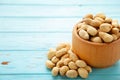 Dried peanuts in wooden bowl on blue wooden background