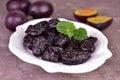 Dried plums or prunes in a plate on a gray background.Close-up.