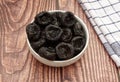 Dried plums in a white bowl isolated on wooden background Royalty Free Stock Photo