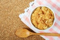 dried pork floss in white cup with wooden spoon on corkboard background.