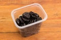 Dried prunes in plastic container on a rustic table Royalty Free Stock Photo