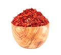 Dried red chili flakes in olive bowl, isolated on white background. Chopped chilli cayenne pepper. Spices and herbs.