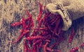 Dried red chili peppers in sack with on old wooden background,Vintage color tone