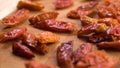 Dried red hot cayenne piripiri peppers falling onto a wooden surface in slow motion.