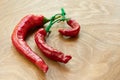 Dried red hot chili pepper as spicy flavoring for meal. A group of bright red Thai Chili peppers with green stem on wooden backgro Royalty Free Stock Photo