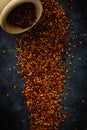 Dried red pepper flakes in a wooden bowl. Chili pepper flakes on a dark background. Top view
