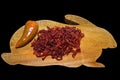 Dried red sweet pepper on antique wood rabbit shaped cutting board.