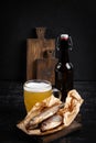 Dried roach fish and glass of beer on dark table, flat lay Royalty Free Stock Photo