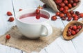 Dried rose hip cup of herbal tea medicinal plants on white black wooden table with wooden shovel and rosehips in burlap sack. Dogr