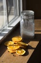 Dried sliced oranges glass jar with sugar inside next to window day light shot