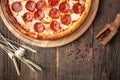 Top view pepperoni pizza on a wooden round board on a wooden background