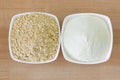 Dried soya milk powder next to cow milk powder in white bowl, top view on wooden background