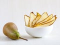 Dried thin slices, green pear fruit chips in white bowl and whole fruit on white Royalty Free Stock Photo