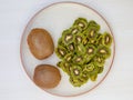 Dried thin slices, heap of green kiwi fruit chips on plate and two whole fruits Royalty Free Stock Photo