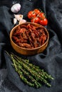 Dried tomatoes with garlic, spices and herbs. Recipe for cooking with ingredients. Black, dark background. Top view Royalty Free Stock Photo