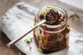 Dried tomatoes in a jar with fresh spices and olive oil