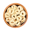 Uncooked, dried tortellini, stuffed dumplings, Italian pasta, in wooden bowl