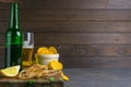 Dried tuna fillet with beer, lemon and potato chips on dark wooden board. Snack on fish with beer. Front views with clear space Royalty Free Stock Photo