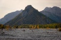 Dried up river bed in a rural countryside with the snowy mountains in the background. Majestic landscape with the rock road and Royalty Free Stock Photo