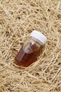 Dried vetiver roots and vetiver essential oil in a glass vial,