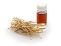 Dried vetiver roots and vetiver essential oil in a glass vial,