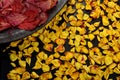 Dried yellow rose petals on a black background and Twisted red leaves on a clay plate Royalty Free Stock Photo