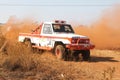 Drifting white Toyota Landcruiser truck kicking up dust on turn