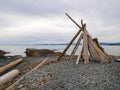 Driftwood Teepee tipi structure on a rock pebble beach by the water on the coastline Royalty Free Stock Photo