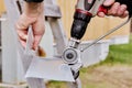 Drill attachment for cutting sheet steel is equipped with rotating metal gearheads, worker cuts edge of galvanized iron. Royalty Free Stock Photo