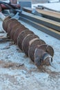 Drill bit on a tractor for installing piles on a construction site