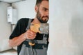 Drilling the hole in wall. The man is making repairs in the apartment