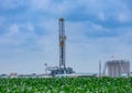 Drilling Rig and oil tanks with green cornfield in the foreground In South Texas Eagle Ford Shale