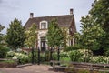 Charming brick rustic house with flowered garden and iron gate in a cloudy day at Drimmelen.