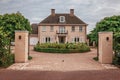 Entrance gate open to courtyard garden in elegant brick house on a cloudy day at Drimmelen.