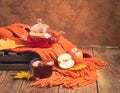 Drink autumn apple red berries in a glass teapot and an orange scarf on a wooden background. Hot fruit berry tea.