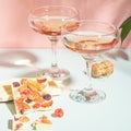 Drink champagne or wine in two elegant glasses and a bar of white chocolate. Gentle pink background bright sunlight.