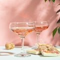 Drink champagne or wine in two elegant glasses and a bar of white chocolate. Gentle pink background bright sunlight. Royalty Free Stock Photo